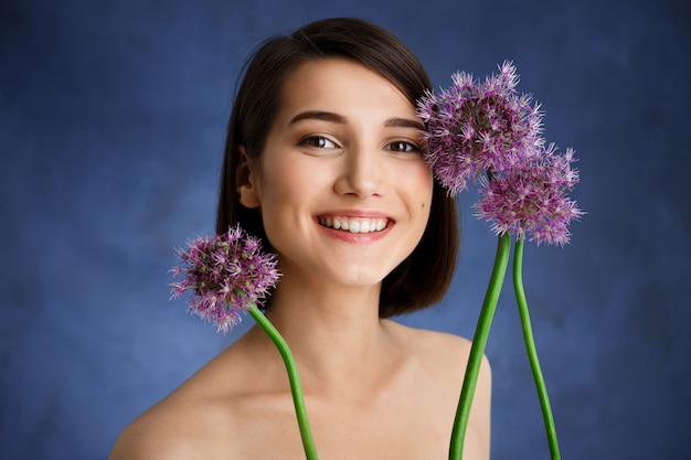 Bouchent portrait de jeune femme tendre avec des fleurs lilas sur mur bleu