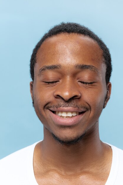 Bouchent le portrait de jeune homme afro-américain en chemise blanche sur l'espace bleu