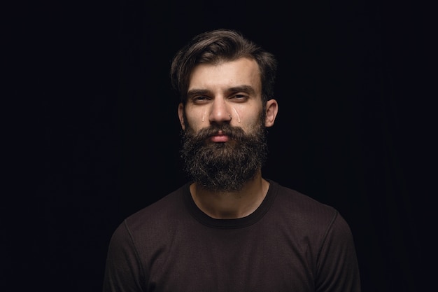 Bouchent le portrait de jeune homme isolé sur l'espace noir. Photoshot des émotions réelles du modèle masculin. Pleurer, triste, morne et désespéré