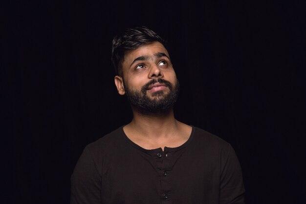 Photo gratuite bouchent le portrait de jeune homme isolé sur fond noir de studio. photoshot des vraies émotions du modèle masculin. rêver et souriant, plein d'espoir et heureux. expression faciale, concept d'émotions humaines.