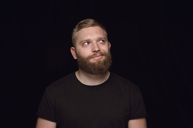 Bouchent le portrait de jeune homme isolé sur fond noir de studio.