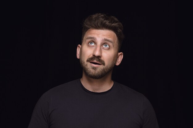 Bouchent le portrait de jeune homme isolé sur fond noir de studio.