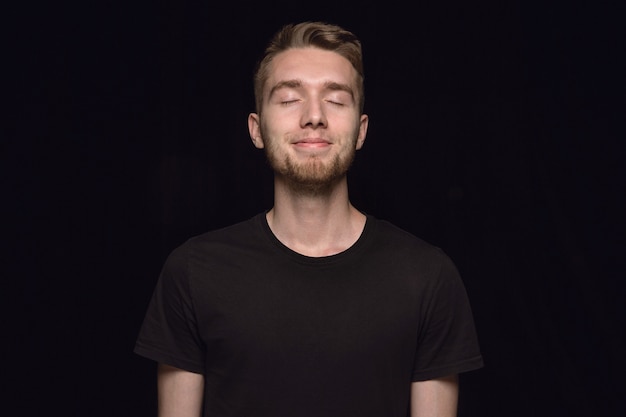 Bouchent le portrait de jeune homme isolé. modèle masculin aux yeux fermés. Penser et sourire. Expression faciale, concept d'émotions humaines.