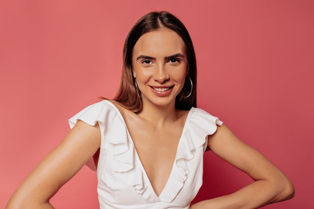 Bouchent Le Portrait De Jolie Femme Heureuse En Haut Blanc Posant Sur Un Mur Rose Avec Un Sourire Heureux