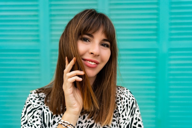 Bouchent le portrait de jolie femme posant sur un mur bleu.