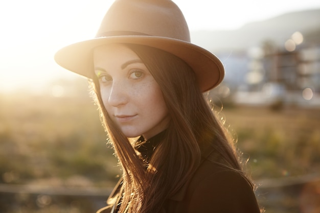 Bouchent le portrait de jolie jeune femme européenne portant chapeau et manteau à la mode