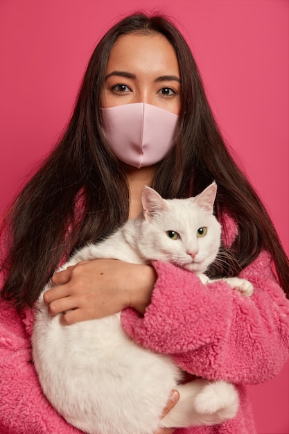 Bouchent le portrait de la jolie jeune femme portant un masque protecteur isolé