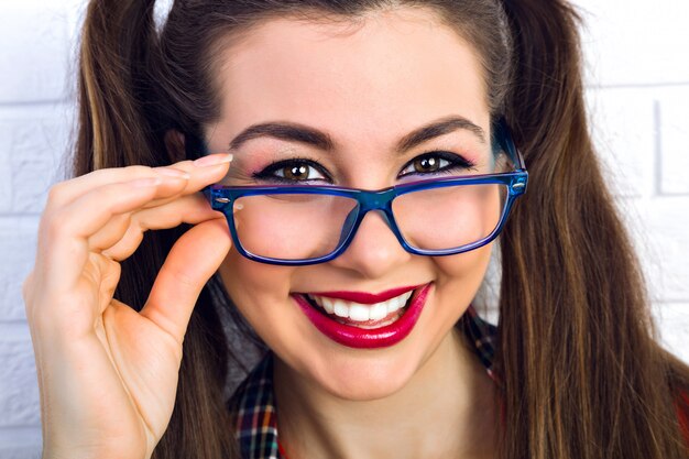 Bouchent le portrait de mode de mode de vie de femme jeune hipster avec maquillage lumineux et étonnants poils bruns moelleux, souriant. Belle femme aux grands yeux noisette.