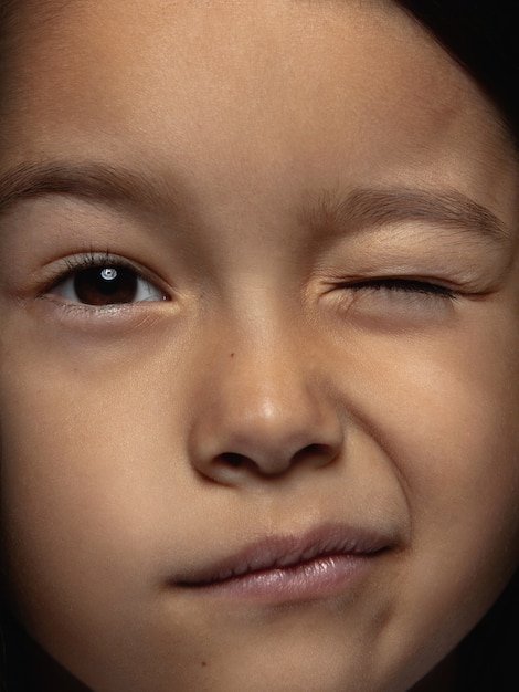 Bouchent le portrait de petite fille asiatique émotionnelle. Séance photo très détaillée d'un modèle féminin avec une peau bien entretenue et une expression faciale brillante. Concept d'émotions humaines. Clignotant, souriant espiègle.