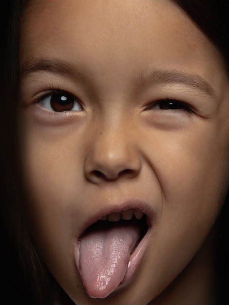 Bouchent le portrait de petite fille asiatique émotionnelle. Séance photo très détaillée d'un modèle féminin avec une peau bien entretenue et une expression faciale brillante. Concept d'émotions humaines. Langue pendante.