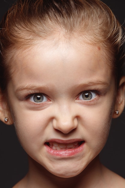 Bouchent le portrait de petite fille caucasienne et émotionnelle. Photo très détaillée d'un modèle féminin avec une peau bien entretenue et une expression faciale brillante. Concept d'émotions humaines. En colère, regardant la caméra.