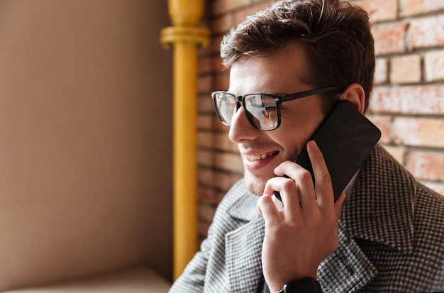 Bouchent la vue latérale de l'homme d'affaires heureux à lunettes