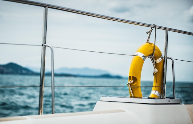 Bouée de sauvetage jaune en gros plan accrochée à un bateau avec un fond d'océan.
