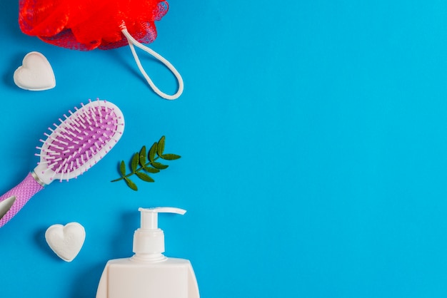 Bouffée de bain; savon; bouteille distributeur et feuilles sur fond bleu