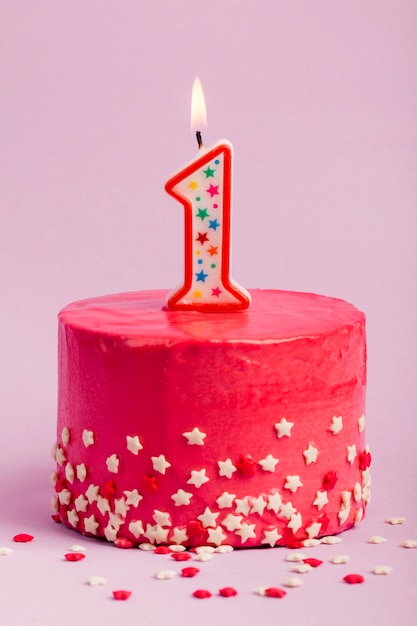 Photo gratuite bougie allumée numéro un sur un gâteau rouge avec une étoile saupoudrée sur fond violet