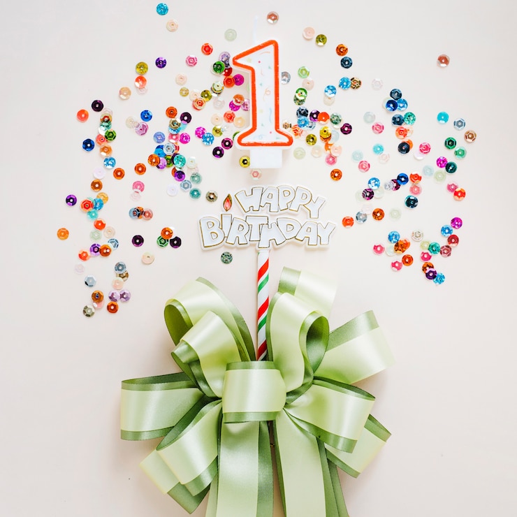Photo gratuit bougie d&#39;anniversaire avec un arc entouré de paillettes