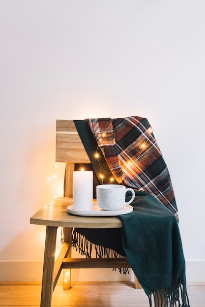 Bougie avec une tasse sur une chaise en bois