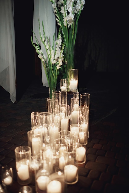 Des bougies brûlent dans de grands vases au sol