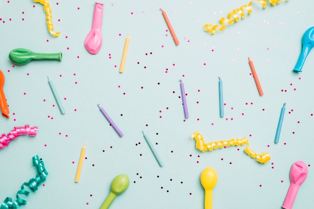 Photo gratuite bougies colorées; ballons dégonflés et banderoles sur fond bleu