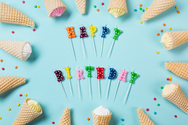 Bougies colorées de joyeux anniversaire décorées avec aalaw dans des cônes de gaufres sur fond bleu