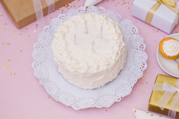 Bougies sur le gâteau d&#39;anniversaire blanc et présente sur fond rose