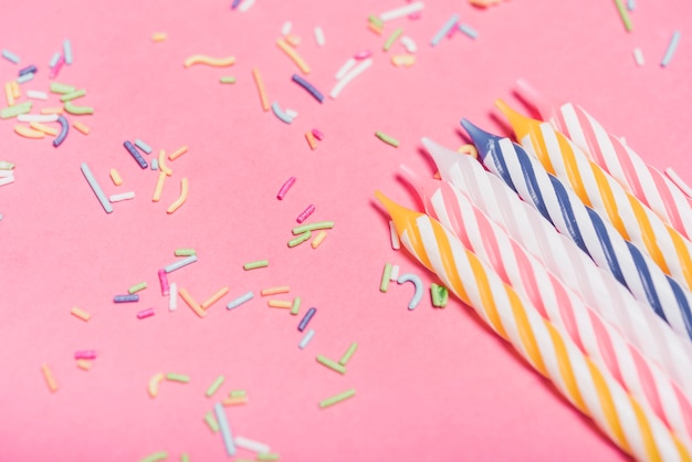 Bougies rayées avec des arrosages colorés sur fond rose