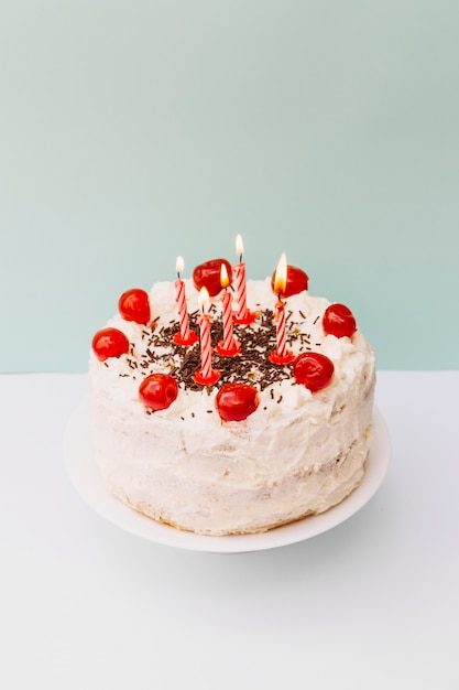 Des bougies à rayures lumineuses sur un gâteau blanc dans un double décor