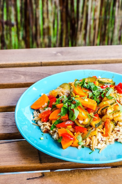 Une bouillie avec de la viande de poulet et des légumes frais coupés sur une plaque bleue sur une table en bois