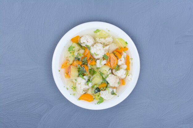 Bouillon de soupe aux légumes hachés et émincés dans une assiette blanche.