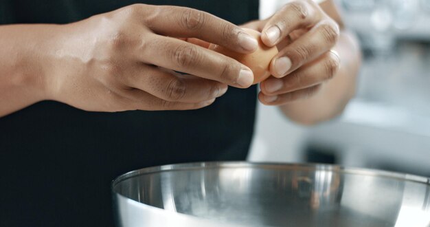 Un boulanger de race mixte fait un gâteau casser des œufs