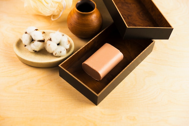 Photo gratuite boule de coton brut et barre de savon à base de plantes sur la table en bois