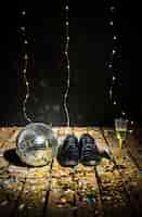 Photo gratuite boule disco, bottes d'homme et verre de boisson entre des confettis