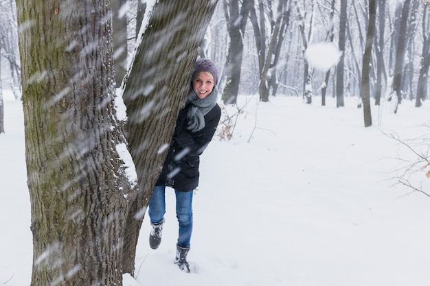 Boule de neige devant une femme souriante, debout derrière l'arbre