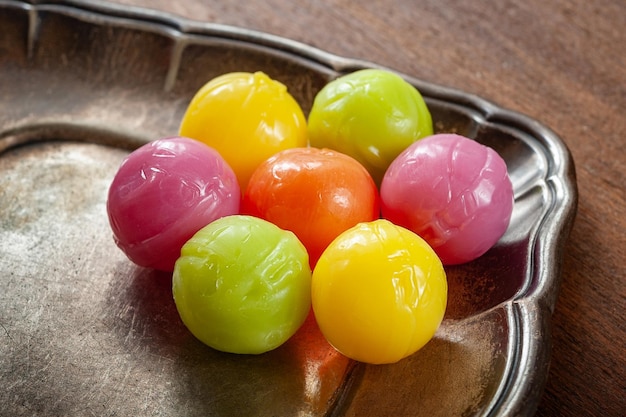 Boules de bonbons. bonbons aux fruits durs à la dragée de couleur empilés sur une soucoupe en argent, fond en bois.