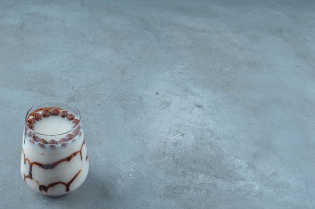 Photo gratuite boules de chocolat dans un verre de lait, sur fond bleu.