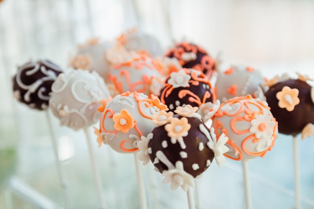 Photo gratuite boules de chocolat avec des fleurs de glacis mis sur des bâtons blancs