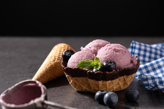 Boules de crème glacée aux bleuets avec gaufre sur fond noir