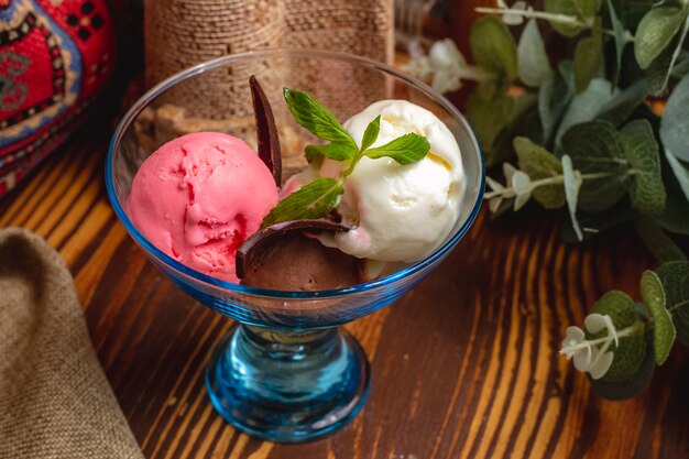 Boules de crème glacée décorées de menthe dans un vase en verre sur une table en bois