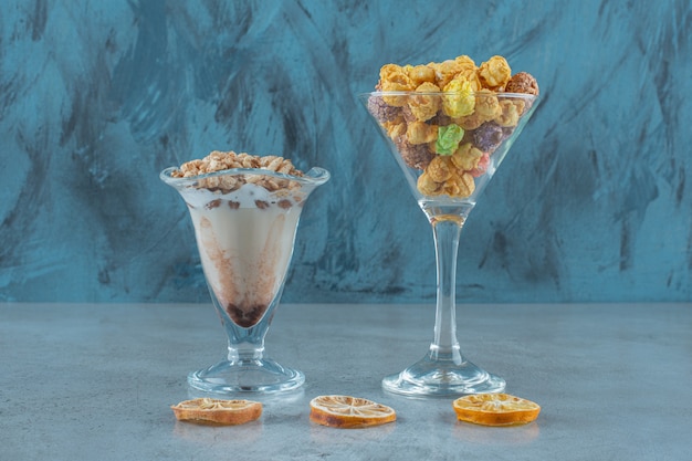Boules de maïs dans un verre et cornflakes dans un verre à café au lait, sur la table bleue.