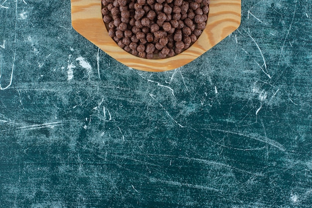 Boules de maïs sucré au chocolat dans une assiette en bois sur la surface bleue