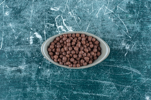 Boules de maïs sucré au chocolat dans un bol, sur fond bleu. photo de haute qualité