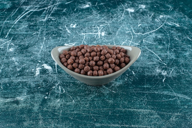 Boules de maïs sucré au chocolat dans un bol, sur la table bleue.