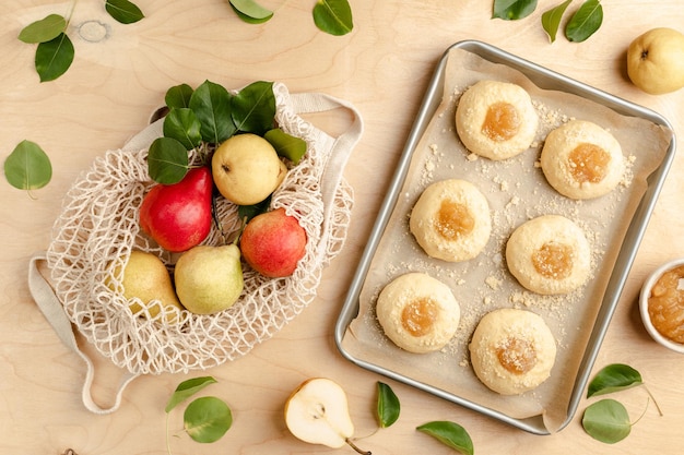 Photo gratuite boulettes brutes faites à la maison à partir de pâte de levure avec de la confiture et des poires fraîches mini tartes recette de cuisson sur fond de bois