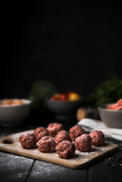 Boulettes de viande sur planche de bois et ingrédients