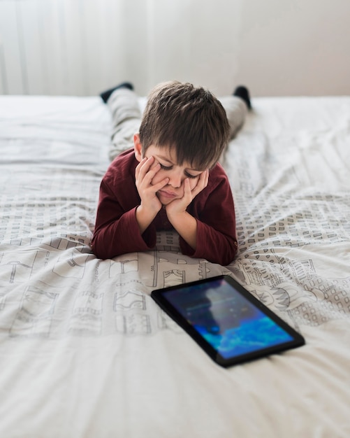 Photo gratuite bouleversé enfant au lit avec tablette