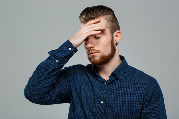 Bouleversé le jeune homme d'affaires prospère posant sur le mur gris.