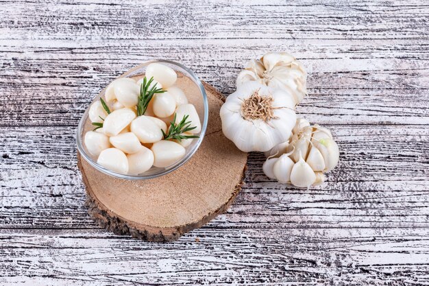 Bouquet d'ail dans un bol sur un dessous de plat sur une table en bois gris. vue de dessus.