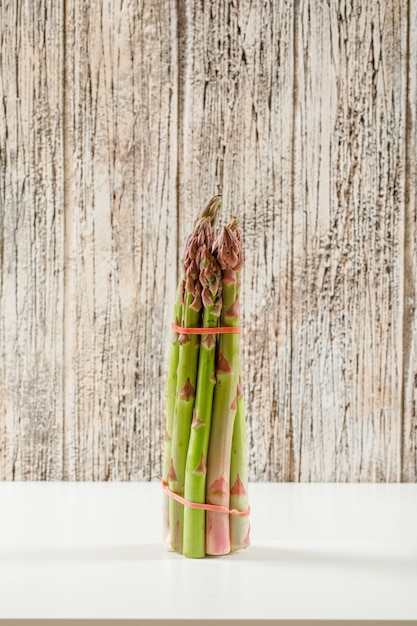 Photo gratuite bouquet d'asperges vertes fraîches sur la surface en bois et blanc grunge