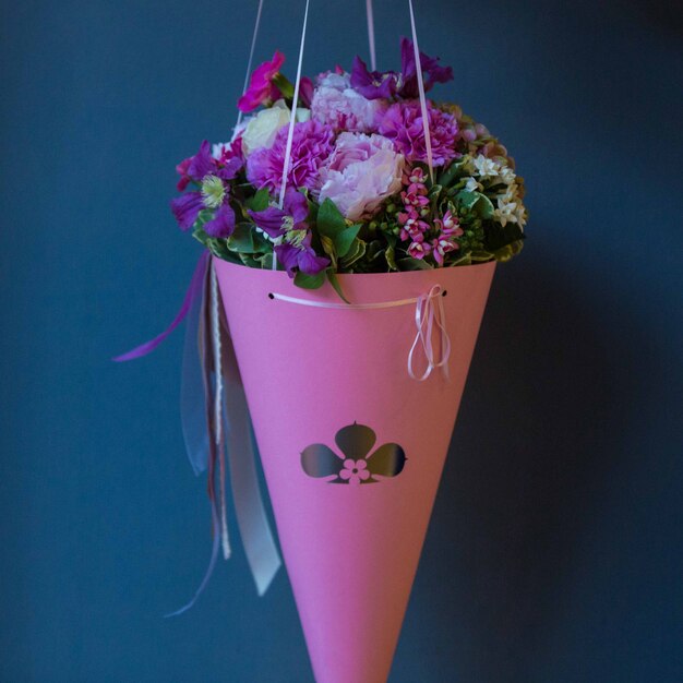 Un bouquet de carton rose de fleurs d'été saisonniers accroché sur un mur de studio