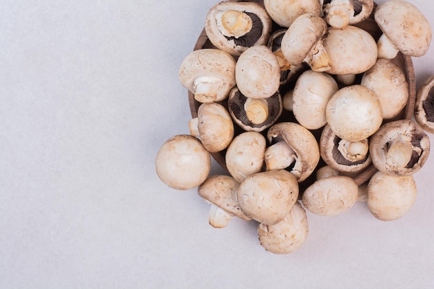 Bouquet de champignons crus sur une surface blanche.